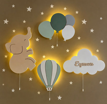 Set de 4 lámparas infantiles de madera con luz LED encendida: elefantito, globos, globo aerostático y nube personalizada con nombre. Decoración de pared en tonos verdes y beige.