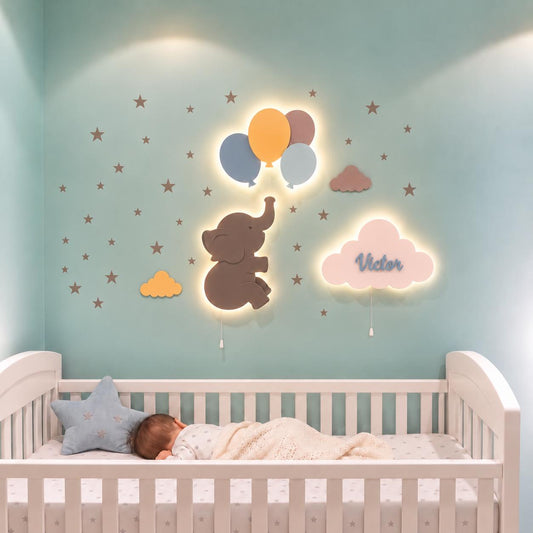 Habitación de bebé con set de 3 lámparas de madera con luz LED: elefantito con globos y nube personalizada con nombre. Decoración de pared en tonos amarillo, gris, azul.